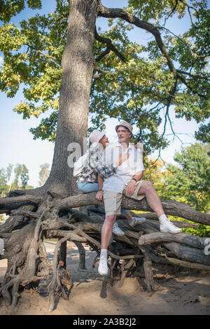 Mature couple walking in the park sitting on the tree roots Stock Photo