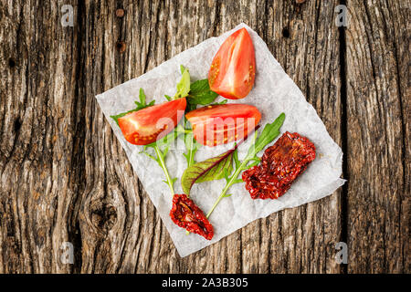 Fresh and sun dried tomatoes on wooden rustic background, top view or flat lay. Minimal composition Stock Photo