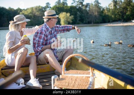 Couple sitting on boat feeding ducks and enjoying the atmosphere Stock Photo