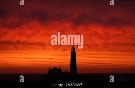 A red sky during sunrise at St Mary's Lighthouse in Whitley Bay on the North East coast. Stock Photo