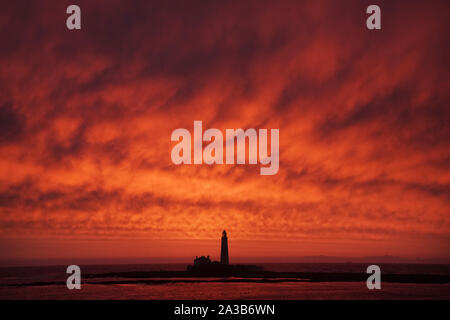 A red sky during sunrise at St Mary's Lighthouse in Whitley Bay on the North East coast. Stock Photo