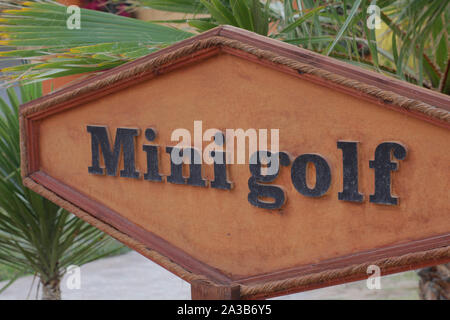 Signpost mini golf. A sign indicating mini golf. Enter the public park, pointing the way. Wooden signboard on which Mini Golf is written. Stock Photo