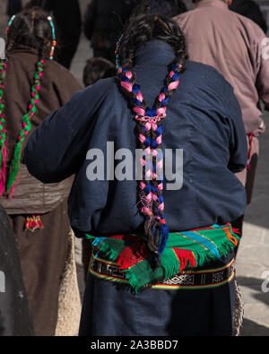 Colored threads are woven into the braids of this older Tibetan woman's traditional hair style in Lhasa, Tibet, on a pilgrimage to the Potala Palace. Stock Photo