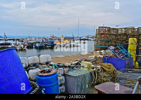 A view of Poole Harbour Haven marina with fishing goods such as nets, crab /  lobster pots on quayside. Fishing boats & pleasure craft moored behind. Stock Photo