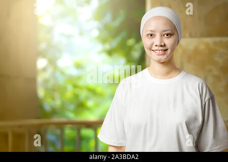 Asian woman in a white shirt with a smile on her face standing at indoor. Cancer awareness Stock Photo