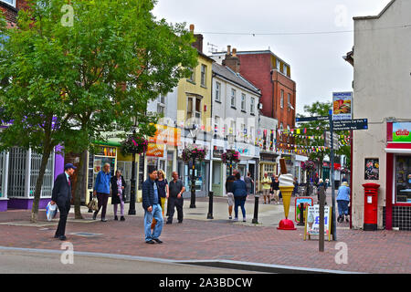 Shoppers and visitors walking along the end of High Street / Castle Street in Poole Old Town, where it leads into the Quay area. Stock Photo