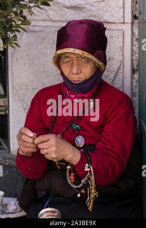 A Tibetan woman holds her mala rosary beads while on a pilgrimage to the Johkhang Buddhist temple in Lhasa, Tibet. Stock Photo