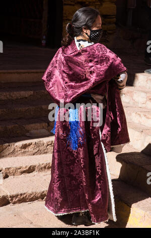 A young Tibetan woman wears an elegant sheepskin-lined silk chupa or chuba coat on a religious pilgrimage to the Drepung Monastery near Lhasa, Tibet. Stock Photo