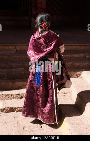 A young Tibetan woman wears an elegant sheepskin-lined silk chupa or chuba coat on a religious pilgrimage to the Drepung Monastery near Lhasa, Tibet. Stock Photo