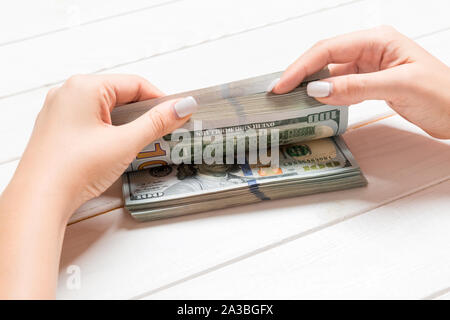 Businesswoman's hands counting one hundred dollar bills on wooden background. Salary and wage concept. Perspective view of Investment concept. Stock Photo