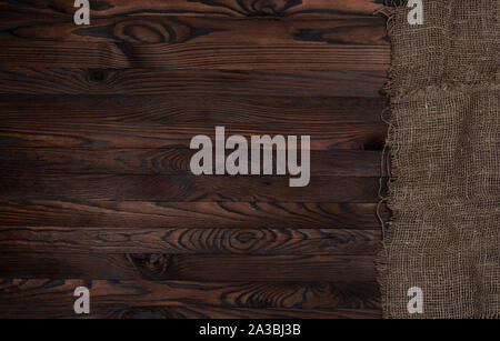 Old burlap fabric napkin on brown wooden background, top view Stock Photo