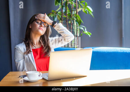 I mistake and lost everything. Portrait of sad beautiful stylish brunette young woman in glasses sitting and holding her head with sadness and shame. Stock Photo