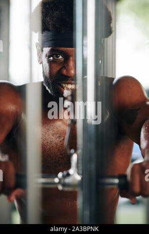 Smiling fit Black man doing exercises with pulldown machine in gym Stock Photo