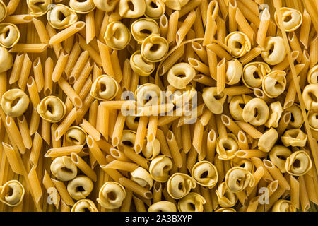 Different types of pasta. Ravioli, penne pasta, tortellini and capellini background Stock Photo