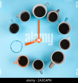 Coffee clocks. Different cups on the blue background with clock hands. Flatlay concept. This image could be used to show coffee break time or morning Stock Photo