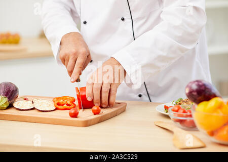 Close up of unrecognizable professional chef cutting vegetables while cooking delicious food in restaurant kitchen, copy space Stock Photo