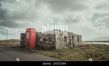 Ruined House with red telephone box by the side of the road in the Outer Hebrides, Benbecula, Stock Photo