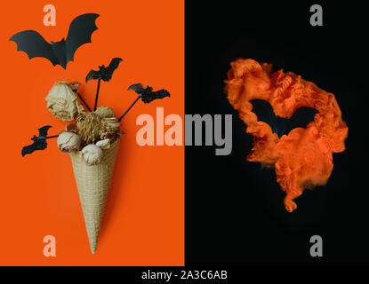 Halloween background with ice cream cone with dried flowers ,bats and orange torch in the shape of a heart, skull on black-orange background.Halloween Stock Photo