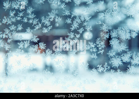 View of the courtyard in winter through a frozen window in snowflakes and hoarfrost. Christmas and winter time concept Stock Photo