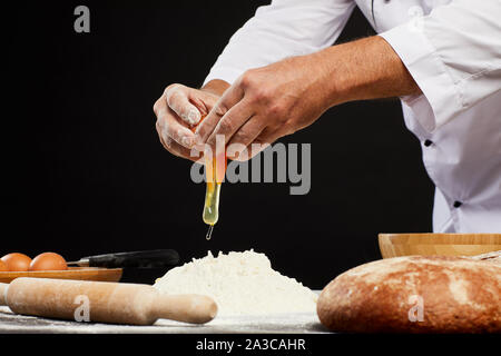 Close up of unrecognizable baker breaking eggs into flour while making traditional bread, copy space Stock Photo