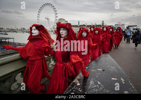 London, UK. 7th Oct, 2019. Extinction Rebellion's 'Red Rebel Brigade' arrive in Westminster in their trademark blood red outfits to join the protests. The environmental campaigners begin a new wave of protest action this morning causing disruption at key sites in London. Credit: Guy Corbishley/Alamy Live News