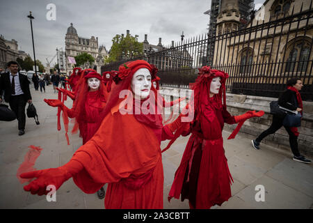 London, UK. 7th Oct, 2019. Extinction Rebellion's 'Red Rebel Brigade' arrive in Westminster in their trademark blood red outfits to join the protests. The environmental campaigners begin a new wave of protest action this morning causing disruption at key sites in London. Credit: Guy Corbishley/Alamy Live News Stock Photo