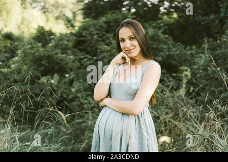 pregnant in a dress in the park Stock Photo
