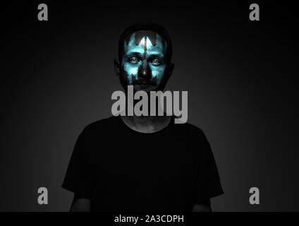 Discover what's inside you. Close up portrait of young man isolated on black studio background. Bright neon light on the face. Halloween, scary look theme, october holidays, horror concept. Stock Photo