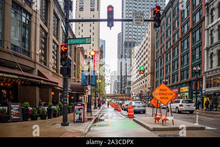 Chicago, Illinois, USA, May 9, 2019. Orange barrels barricade the under construction street. Warning signal for the drivers, city background. Stock Photo