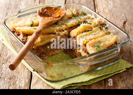 Cutting out a piece of lasagna Puerto Rican pastelon close up in baking dish on the table. horizontal Stock Photo