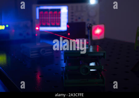 Experiment in optic lab with laser device. Red laser on optical table in physics laboratory Stock Photo