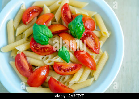 simple Italian pasta with olive oil, fresh tomatoes and basil. Stock Photo
