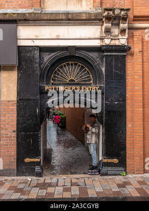 A Busker playing in the entrance to Pottingers Entry, Belfast, Northern Ireland, UK - September 26, 2019 Stock Photo
