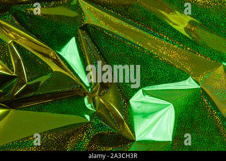 Creative photo background of gold holographic  crumpled foil with green highlights and shadows Stock Photo