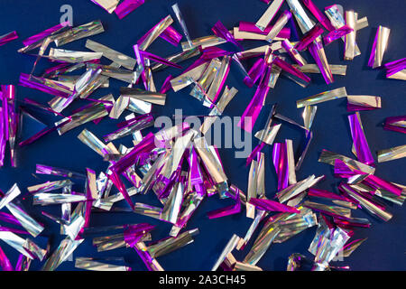 Photo background of rectangular confetti made of purple and silver foil on the dark blue background. Stock Photo
