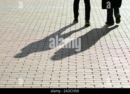 Legs and shadows of people on pavement Stock Photo