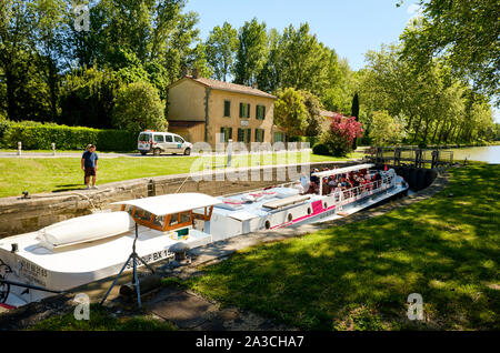 The Surcouf tourist cruise flat boat in the Emborrel Locks on the Canal du Midi waiting for water level to rise to continue travel Stock Photo