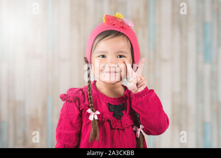 Cute little asian girl showing PEACE hand gesture. Concept of happiness and carefree Stock Photo