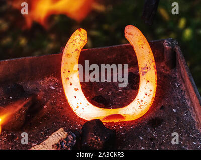 Blacksmith working on the anvil, making a horseshoe. Traditional tools for craft in workshop. Blacksmith occupation concept. Stock Photo