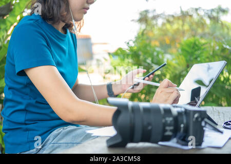 Photographer sitting and editing photos using a tablet. Portable size, smart features In a coffee shop or café Stock Photo