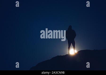 A man stands on a rock and watches a super moon rise on a spring night. Stock Photo