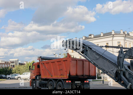 Road repair work. Cold milling machine removing old pavement from a street surface. Stock Photo