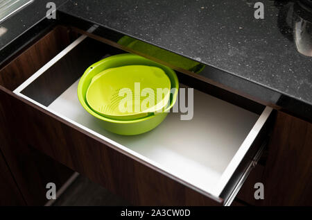 Green salad bowl and bowl for straining food from water in the kitchen drawer. Stock Photo