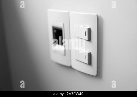 White switch on a white wall with two switches and one common switch. Stock Photo