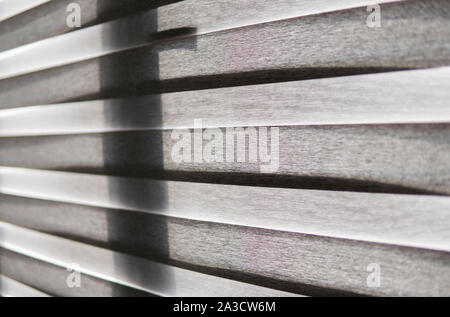 Details of brown fabric roller blinds on the plastic window with wood texture in the living room. Stock Photo