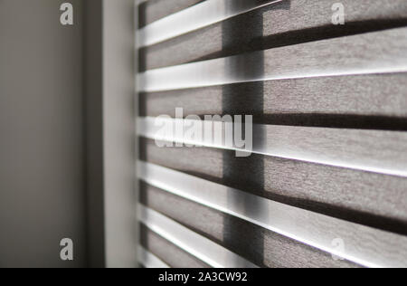 Details of brown fabric roller blinds on the plastic window with wood texture in the living room. Stock Photo