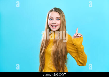 Photo of energetic nice smiling lady isolated on blue background pointing her finger in eureka sign, having great innovative idea Stock Photo