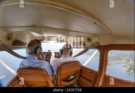 Pilot and co-pilot in a Cessna 172 airplane flying over Megalo Amoni, Corinthia, in the Saronic gulf , Greece Stock Photo