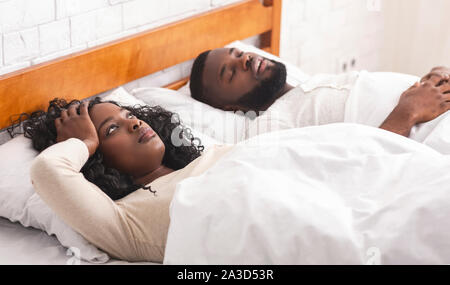 Upset wife annoyed by snoring husband, lying sleepless in bed Stock Photo