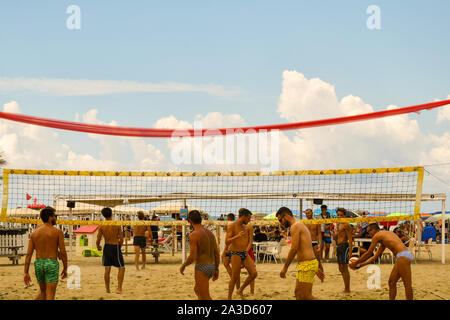 Young men playing beach volleyball on the seashore of Lido di Camaiore in a sunny mid-August day, Versilia, Tuscany, Italy Stock Photo